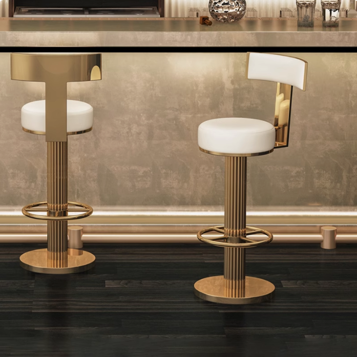 Luxury gold-plated stainless steel bar stool with a milky white microfiber leather round seat and curved backrest, positioned against a modern dark bar backdrop.