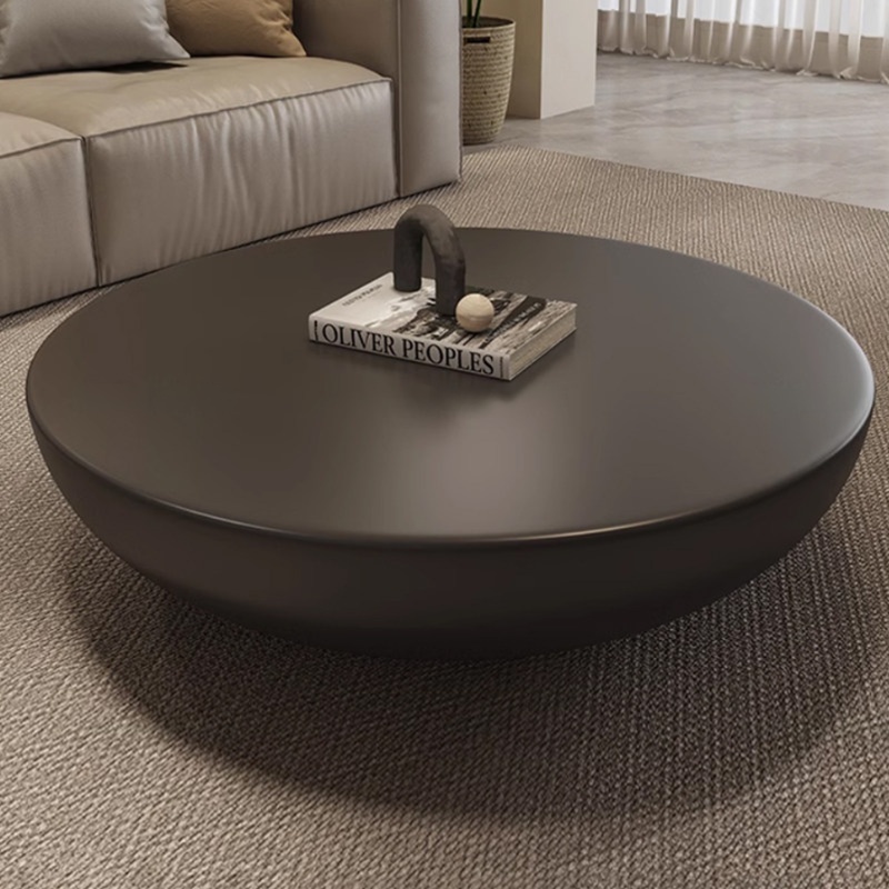 Modern minimalist 90cm matte black round hemisphere coffee table crafted from FRP fiberglass, styled with a design book on a textured neutral rug in a luxury living room.