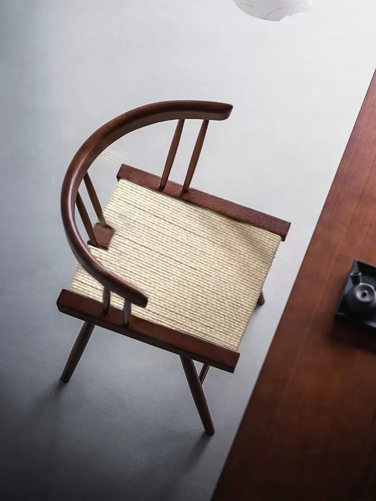 Solid wood round back dining chair with curved armrest and hand-woven rope seat in walnut finish, modern coastal style for dining room or café interiors.