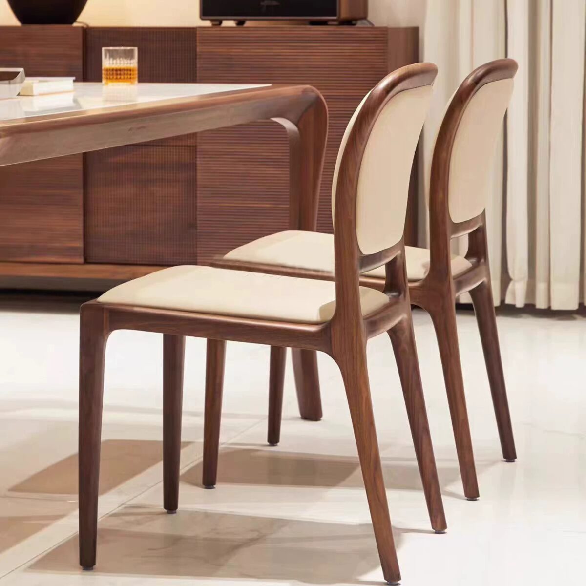 Luxury dark brown solid wood dining chair with cream scratch-resistant leather upholstery and ergonomic high back design in a modern dining room interior.