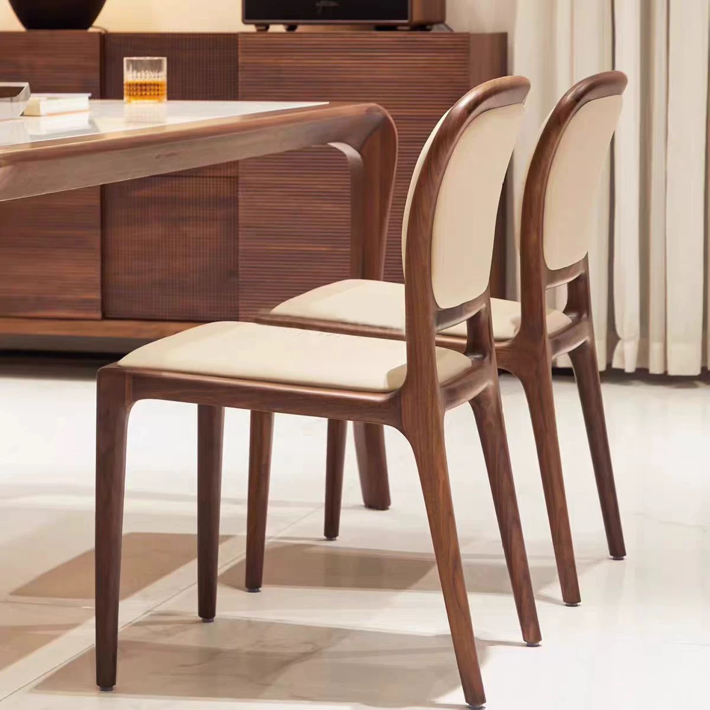 Luxury dark brown solid wood dining chair with cream scratch-resistant leather upholstery and ergonomic high back design in a modern dining room interior.